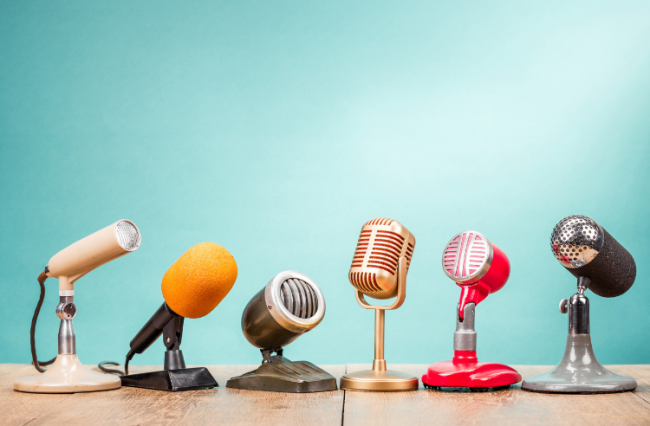 A row of microphones from various historical times on a table